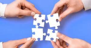 Four hands holding puzzle pieces