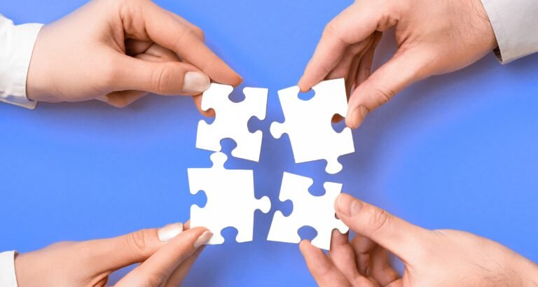 Four hands holding puzzle pieces
