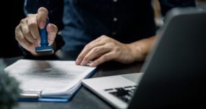A person stamping some documents with a notebook in front of her