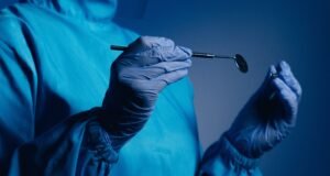 A Doctor or dentist holding a medical device in their hands.