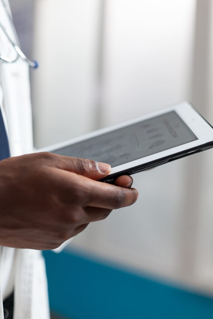 Man holding a tablet. Wearing medical attire and in a hospital setting. Regulatory Affairs.