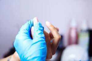 Manicurist examining client's nails to determine if fiberglass nails are suitable.