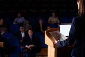 Rear view of female business executive giving a speech. MDR and IVDR,