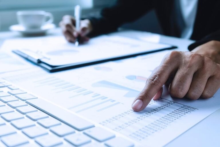 Women's hands pointing to information in documents in a business setting.